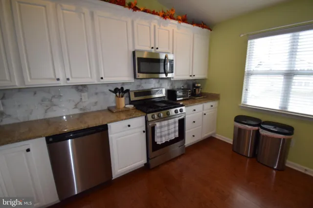 a kitchen with granite countertop a stove a sink and a microwave