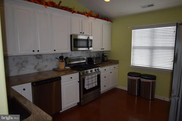 a kitchen with stainless steel appliances white cabinets and a stove top oven