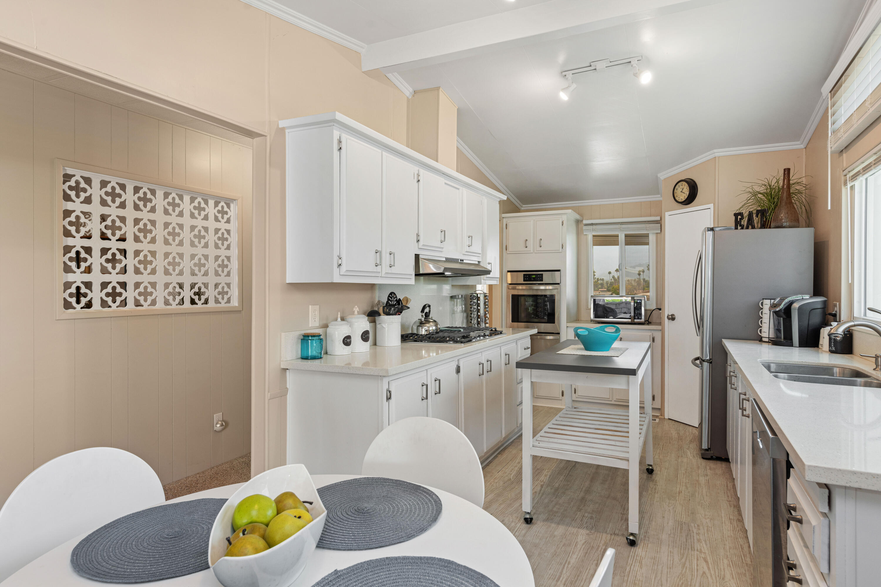 Undisclosed Address Palm Desert, CA 92260 - Photo 12 of 41 a kitchen with stainless steel appliances a white refrigerator a sink dishwasher a dining table and chairs with wooden floor