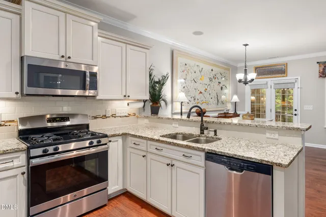 a kitchen with granite countertop a sink cabinets stainless steel appliances and a window