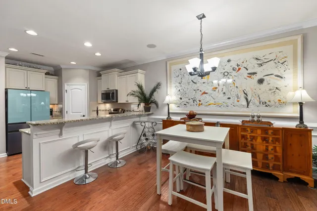 a kitchen with stainless steel appliances granite countertop a stove top oven a refrigerator a sink and white cabinets with wooden floor