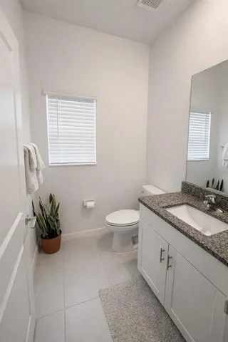 a bathroom with a granite countertop sink a toilet and with mirror
