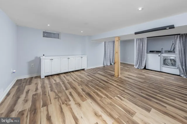 a view of empty room with wooden floor and kitchen