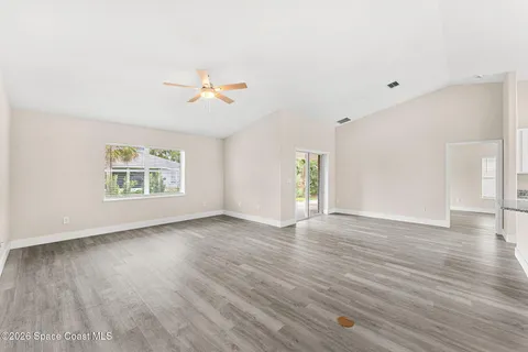 a view of an empty room with a window and wooden floor