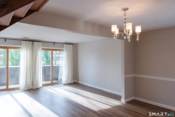 an empty room with wooden floor chandelier and windows