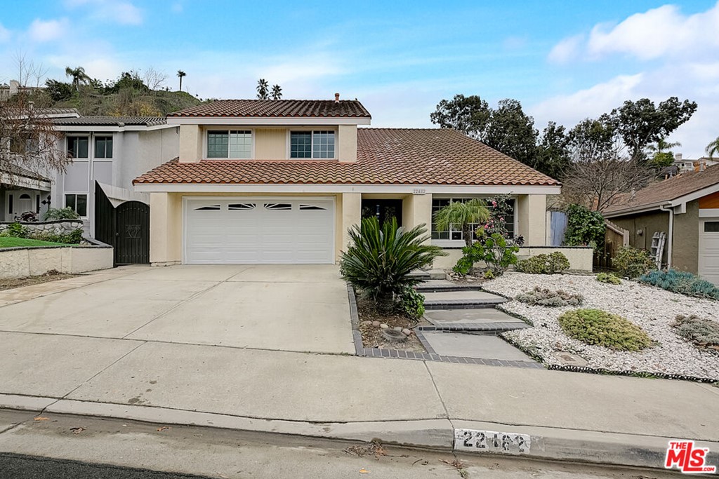 a front view of a house with garage and plants