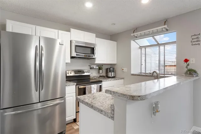 a kitchen with stainless steel appliances granite countertop a refrigerator a sink a stove a microwave and island