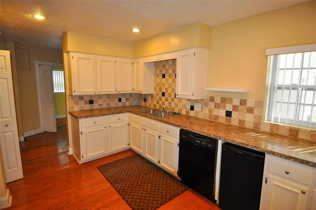 a large kitchen with granite countertop a sink a window stainless steel appliances and cabinets