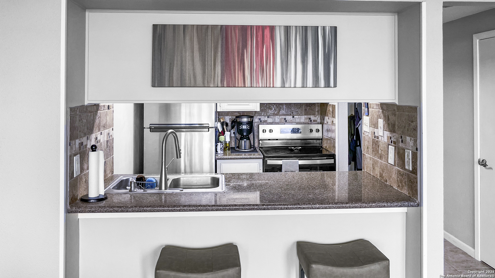 7701 Wurzbach Road, Unit 703 San Antonio, TX 78229 - Photo 9 of 28 a kitchen with kitchen island granite countertop a refrigerator a stove and a sink with wooden floor