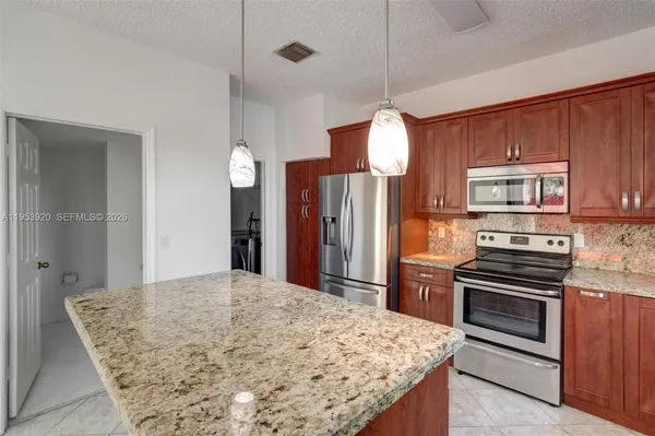a kitchen with stainless steel appliances kitchen island granite countertop a stove a sink and a refrigerator