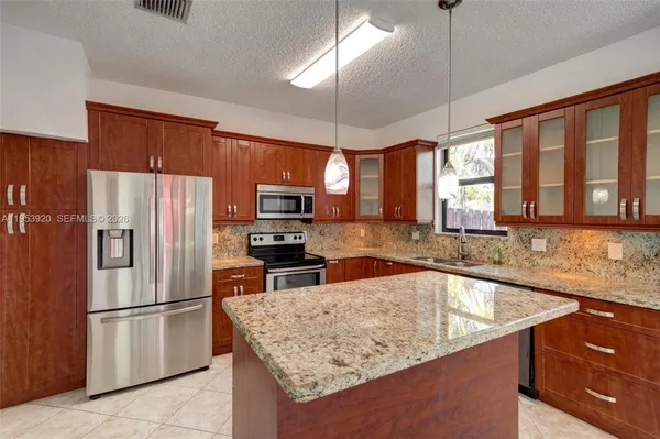 a kitchen with stainless steel appliances granite countertop a refrigerator a sink a stove a dining table and chairs