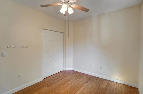a view of an empty room with wooden floor and a window