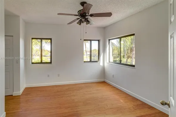 a view of empty room with wooden floor and fan