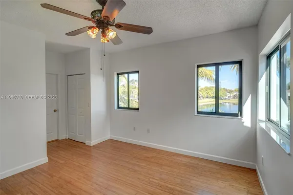 a view of an empty room with window and wooden floor