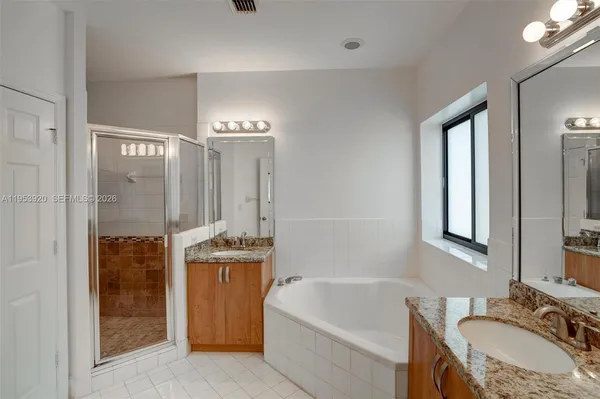 a bathroom with a granite countertop tub sink a mirror and shower