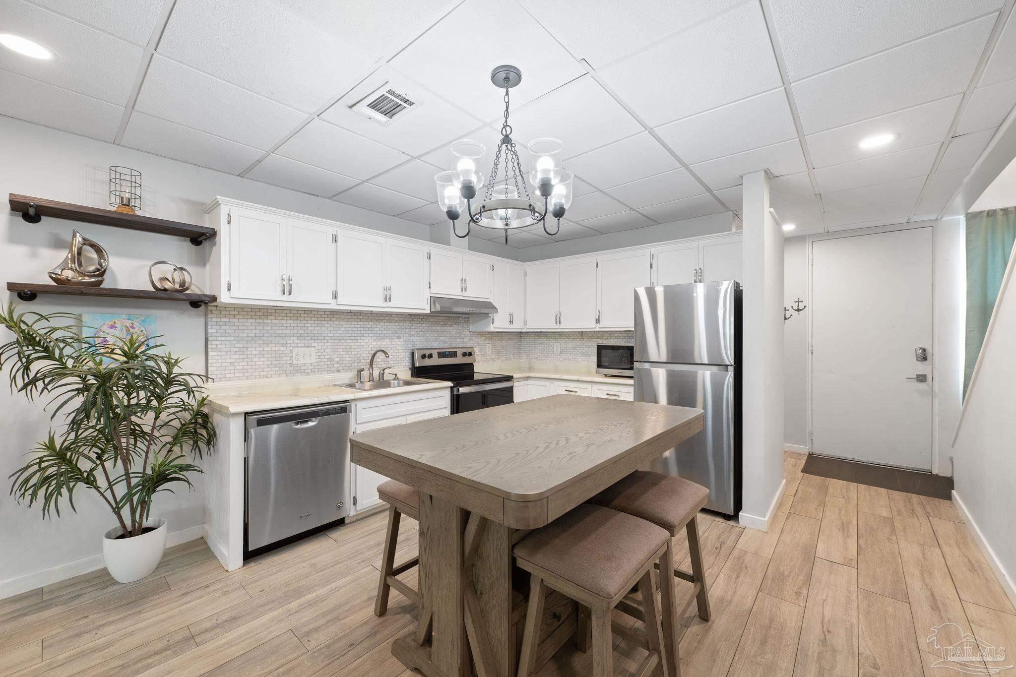 201 Pensacola Beach Road, Unit D24 Gulf Breeze, FL 32561 - Photo 5 of 29 a kitchen with stainless steel appliances granite countertop a refrigerator a stove a sink dishwasher and a dining table with wooden floor