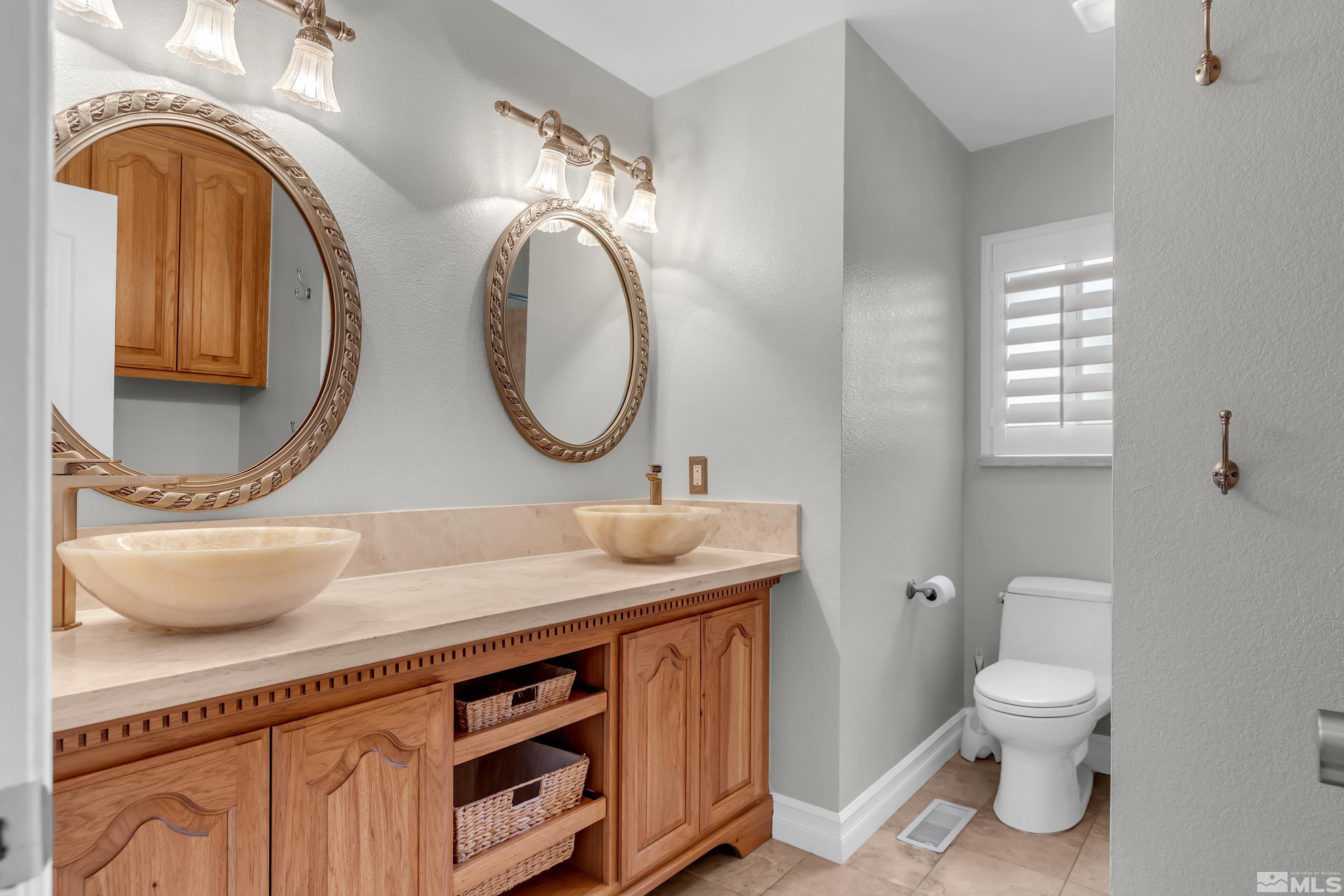 2370 Fireside Circle Reno, NV 89509 - Photo 21 of 29 a bathroom with a granite countertop toilet a sink and a mirror