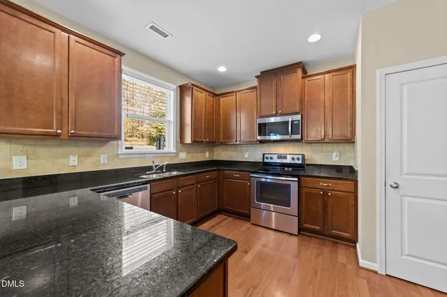 a kitchen with stainless steel appliances granite countertop a stove a sink and a microwave