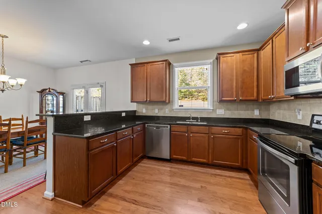 a kitchen with stainless steel appliances granite countertop wooden cabinets a sink and a stove
