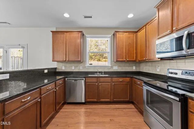 a kitchen with granite countertop wooden floors and stainless steel appliances