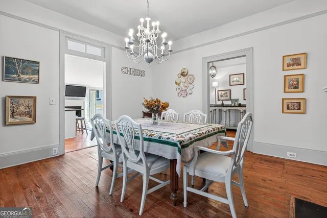 a dining room with wooden floor a chandelier a wooden table and chairs