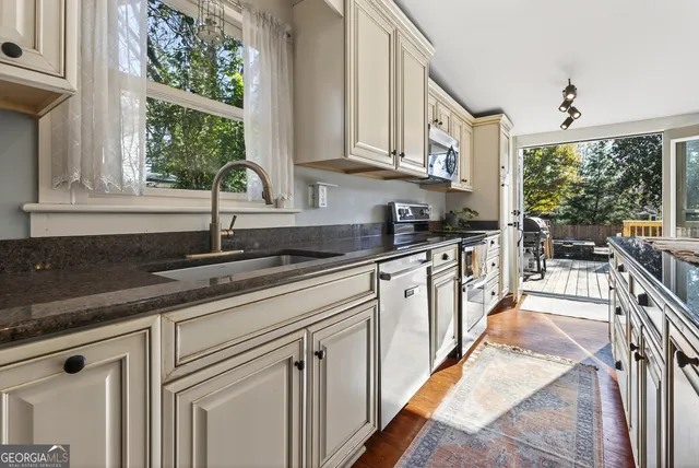 a kitchen with stainless steel appliances granite countertop a sink a stove and a granite counter tops with a large window