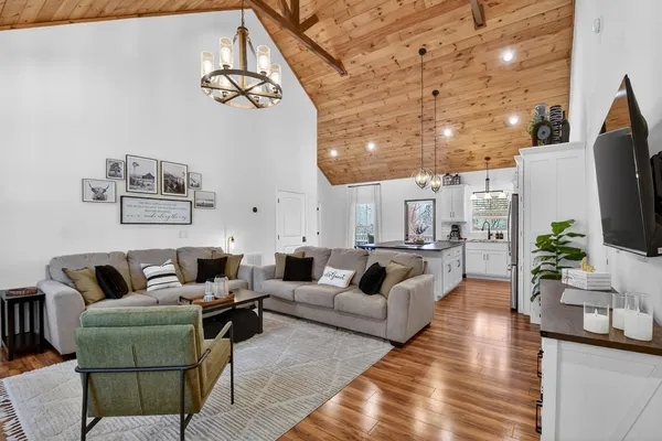 a living room with furniture a chandelier and a flat screen tv