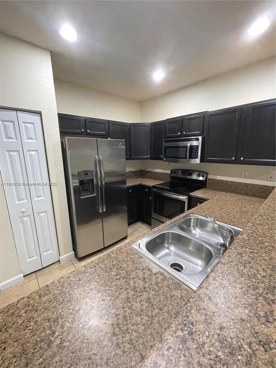 3217 Southeast 4th Street Homestead, FL 33033 - Photo 12 of 20 a kitchen with a sink a stove a microwave a counter top space and cabinets