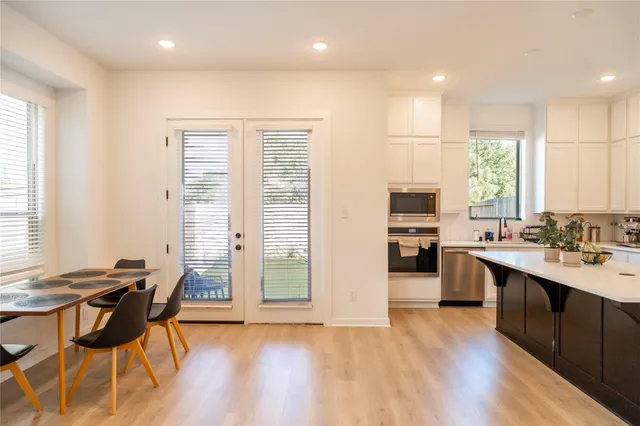 a kitchen with stainless steel appliances granite countertop a stove top oven a sink dishwasher a dining table and chairs with wooden floor