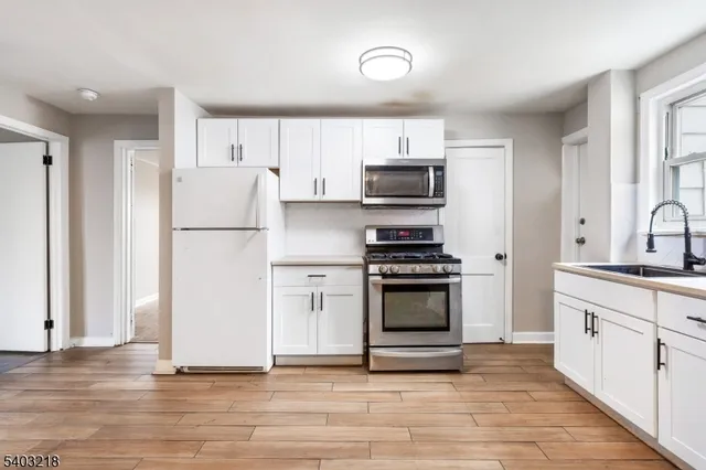 a kitchen with stainless steel appliances a refrigerator stove and white sink