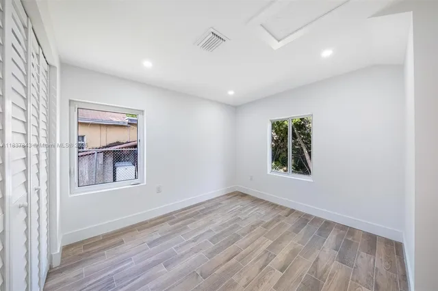 an empty room with a window and wooden floor