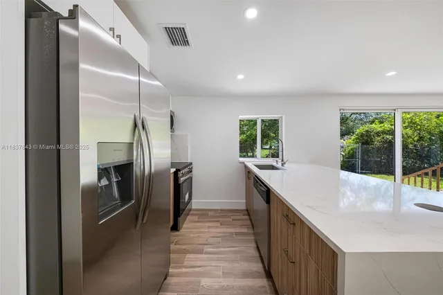 a kitchen with stainless steel appliances granite countertop a refrigerator and a sink