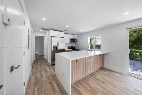 a kitchen with kitchen island wooden floors appliances and cabinets