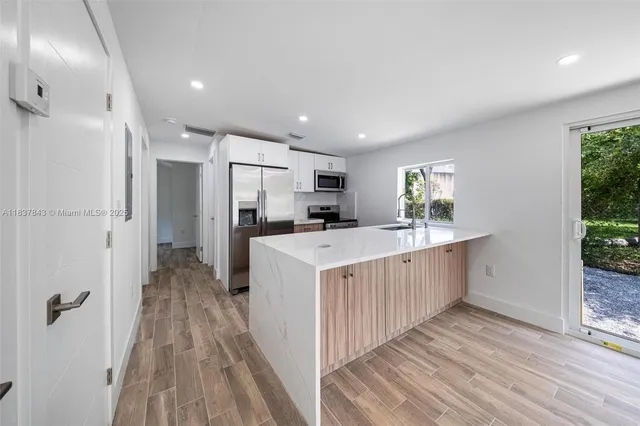 a kitchen with kitchen island wooden floors appliances and cabinets