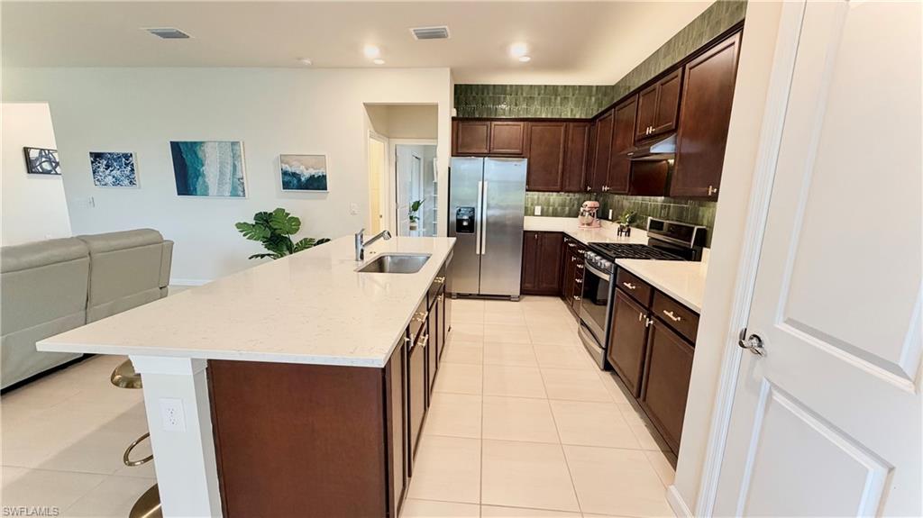2085 Yellowfin Circle Naples, FL 34114 - Photo 10 of 50 a large white kitchen with kitchen island a stove a sink a refrigerator and cabinets