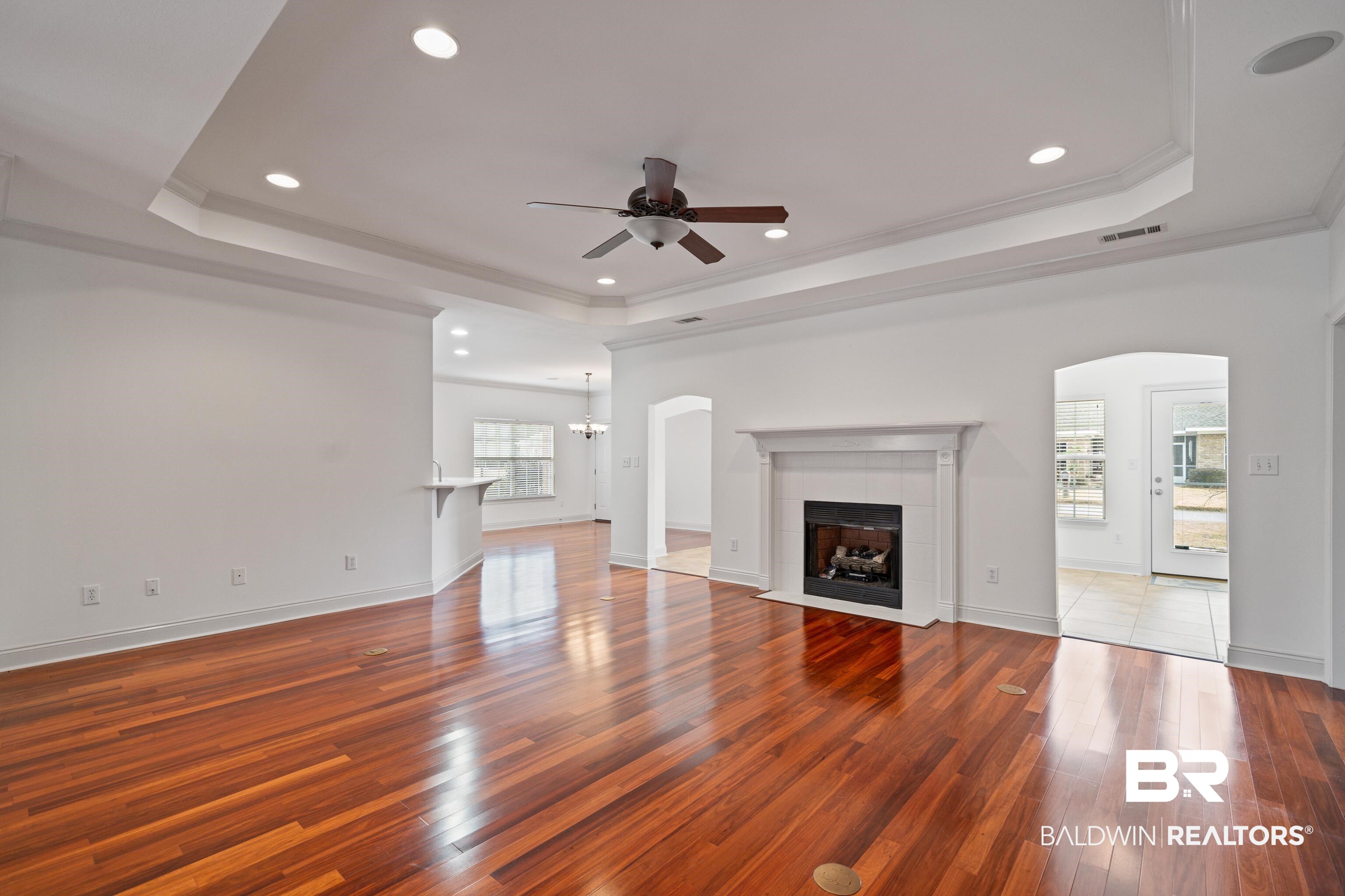 404 Savannah Lane Foley, AL 36535 - Photo 8 of 29 Unfurnished living room with crown molding, a fireplace, recessed lighting, a raised ceiling, and wood finished floors