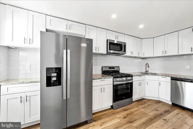 a kitchen with granite countertop a sink cabinets and stainless steel appliances