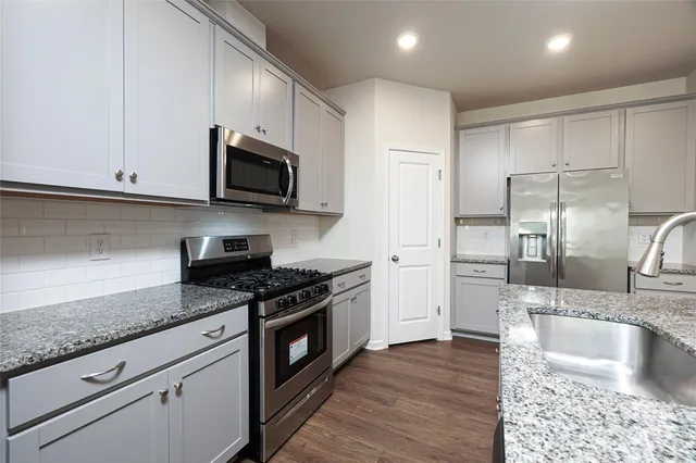 a kitchen with granite countertop a sink stainless steel appliances and cabinets