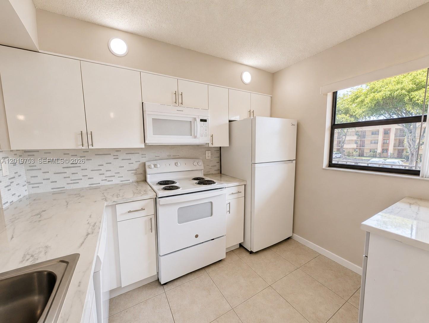 3410 Foxcroft Road, Unit 206 Miramar, FL 33025 - Photo 5 of 23 a kitchen with a stove a refrigerator and a sink