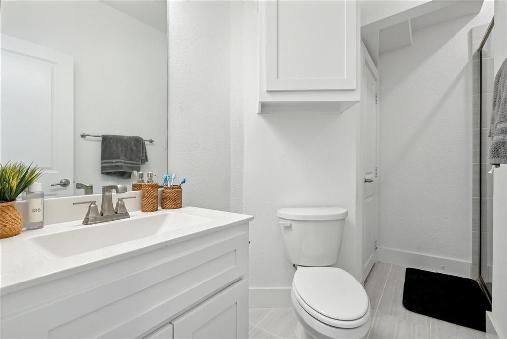 1710 Highwood Road Forney, TX 75126 - Photo 8 of 25 Bathroom featuring a white vanity with an integrated sink, polished chrome faucet, a wall-mounted mirror, and a white toilet