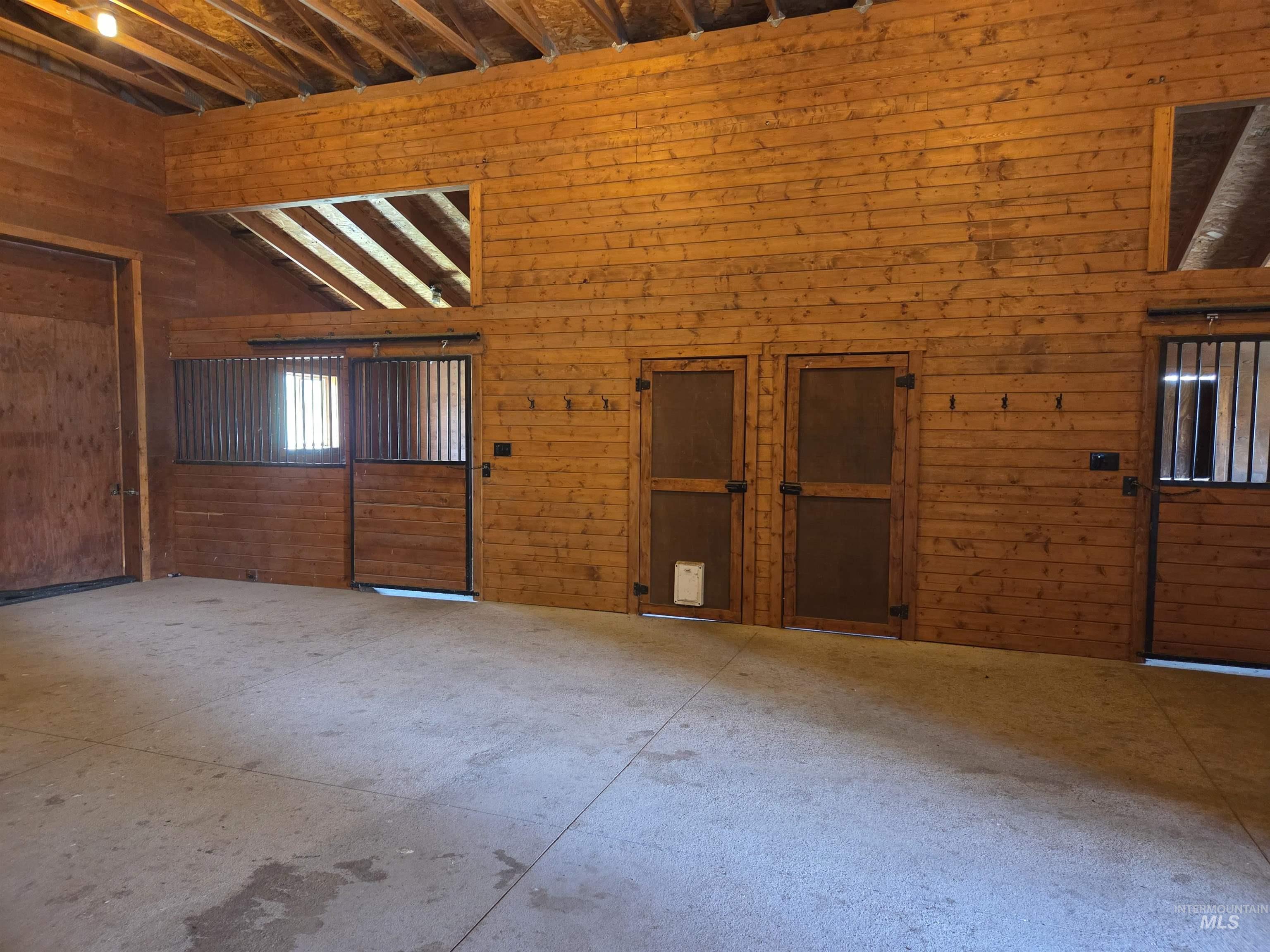 1085 Wallen Road Moscow, ID 83843 - Photo 40 of 50 Interior barn featuring wood-finish wall paneling, sliding stall doors with metal grates, and concrete flooring