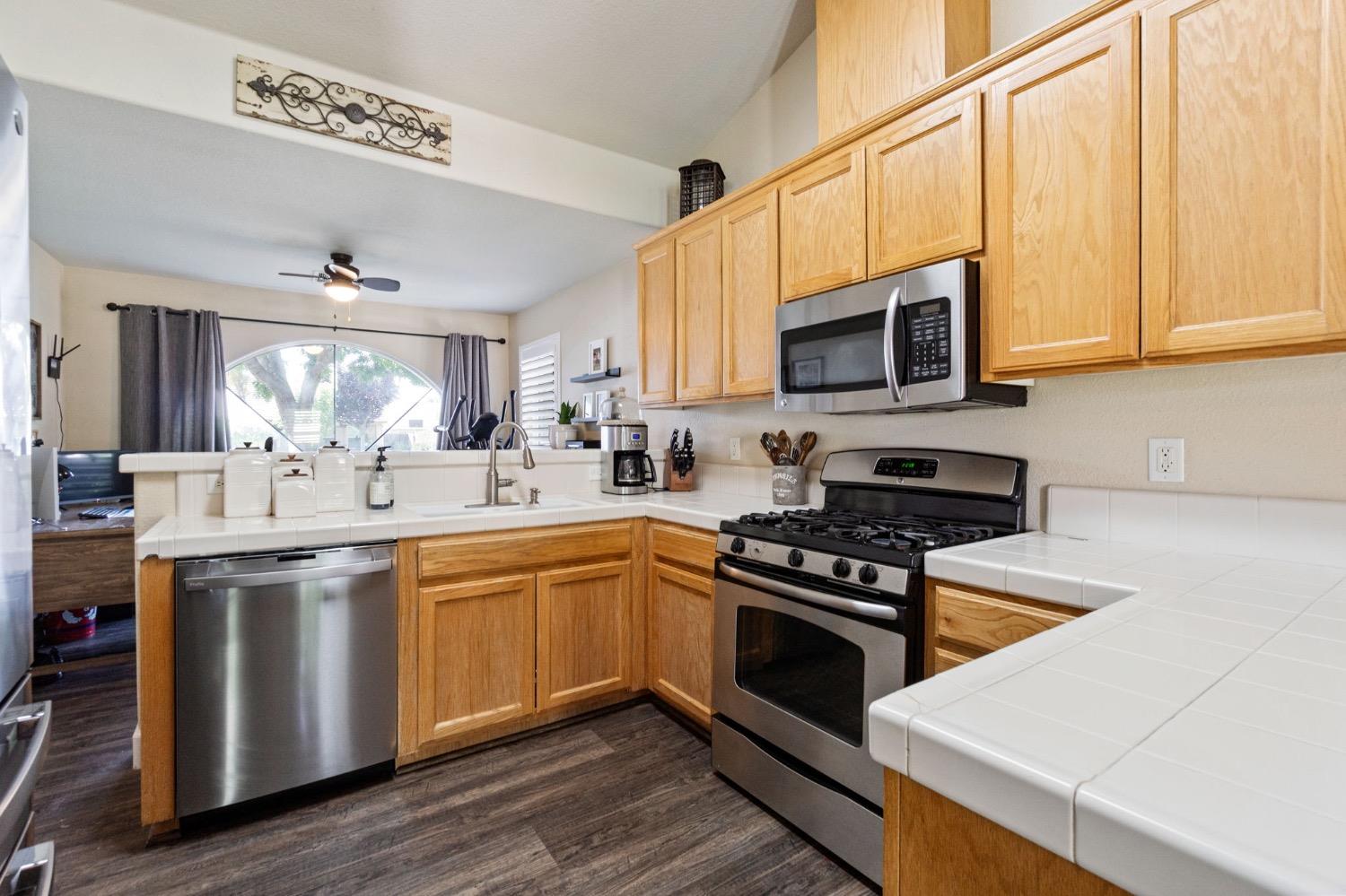595 Quady Lane Madera, CA 93637 - Photo 12 of 25 a kitchen with stainless steel appliances a stove sink microwave and cabinets