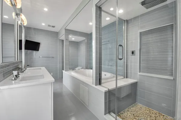a bathroom with a tub a sink shower and mirror