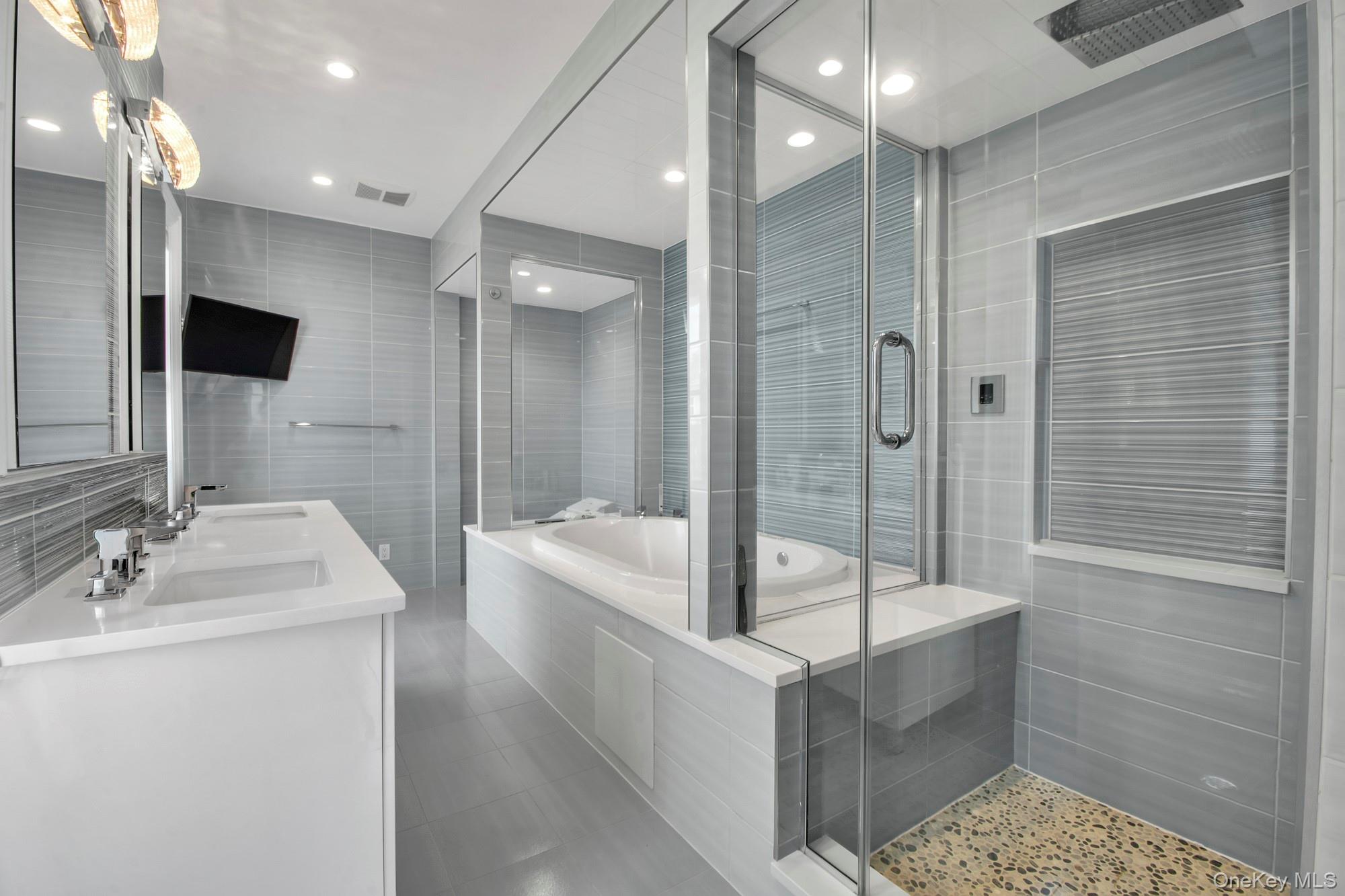 102 Shore Road Queens, NY 11363 - Photo 13 of 22 Primary en suite bath with tile walls, double vanity, soaking tub, a stall shower, and light tile patterned floors, radiant heat