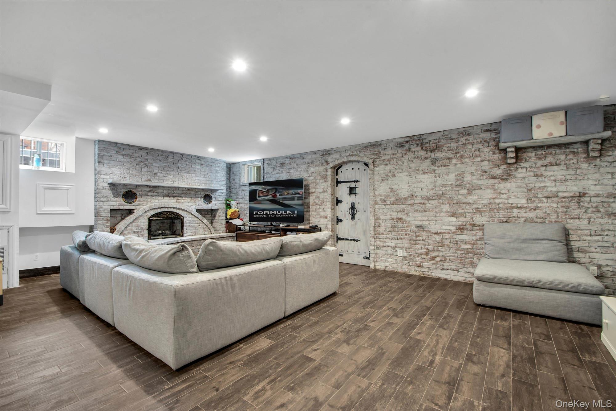 102 Shore Road Queens, NY 11363 - Photo 21 of 22 Bright windowed living room with wood-type flooring, a fireplace, brick wall, and recessed lighting