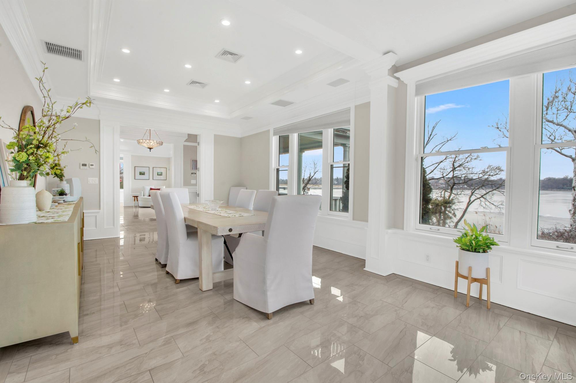 102 Shore Road Queens, NY 11363 - Photo 10 of 22 Dining room featuring water views, recessed lighting, ornamental molding, a decorative wall, and a tray ceiling, radiant heat flooring