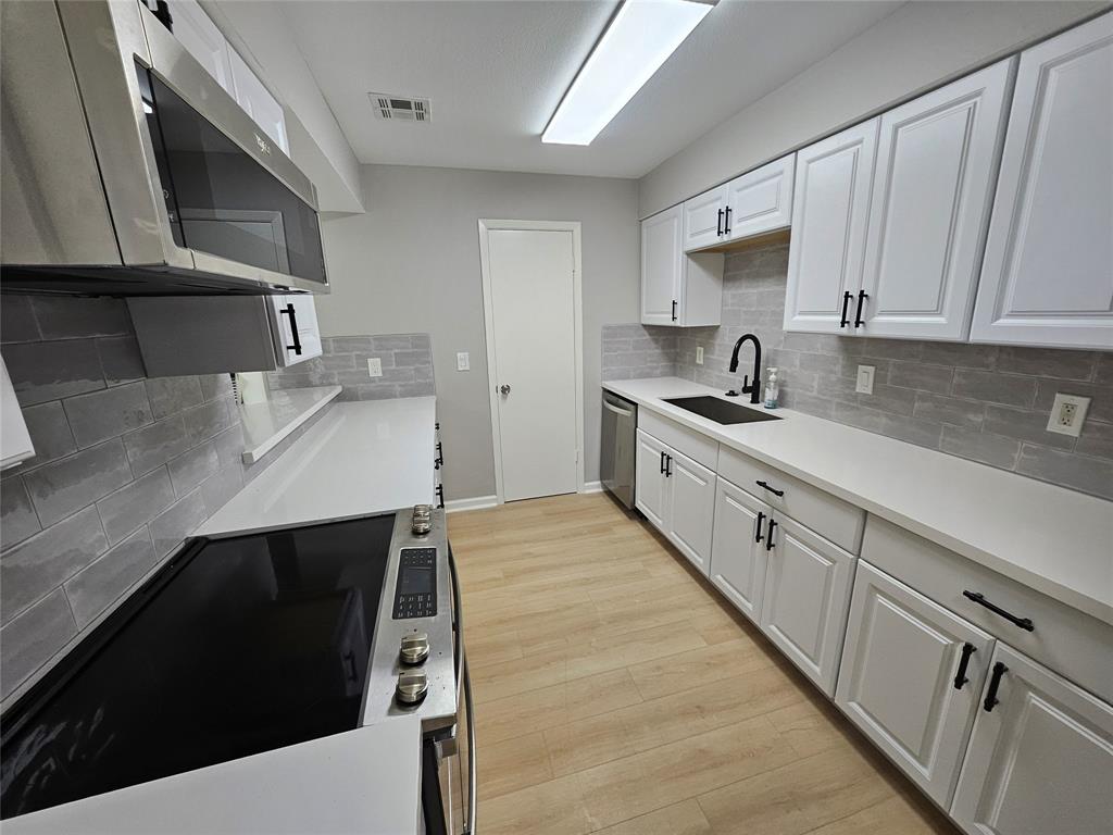 a kitchen with stainless steel appliances a sink dishwasher a stove and cabinets