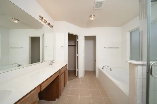 a spacious bathroom with a tub sink and mirror