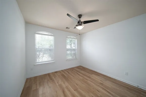 a view of empty room with wooden floor and fan