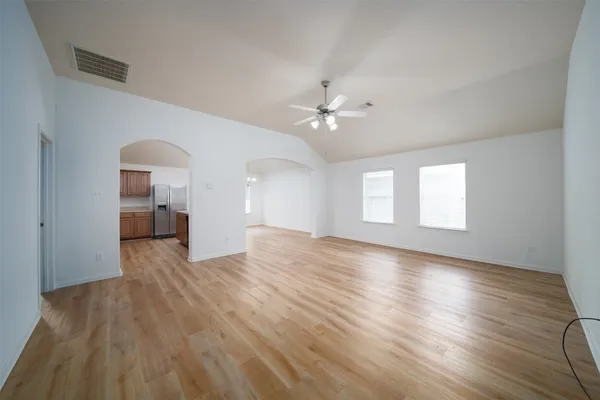 a view of an empty room with a window and wooden floor